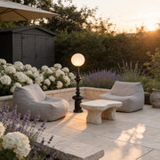 Outdoor black floor lamps with a sleek design, enhancing a garden patio with white furniture.