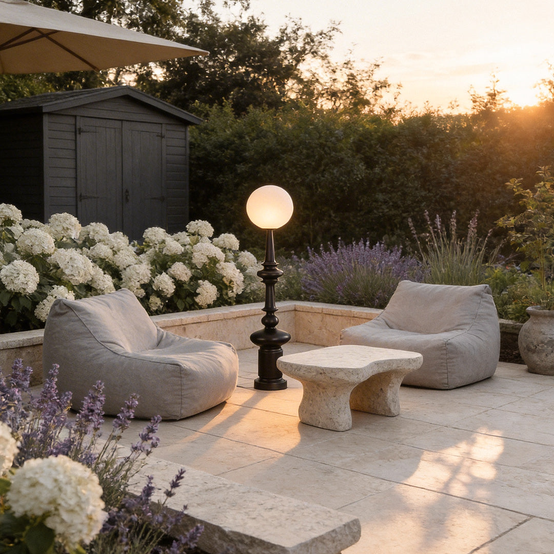 Outdoor black floor lamps with a sleek design, enhancing a garden patio with white furniture.