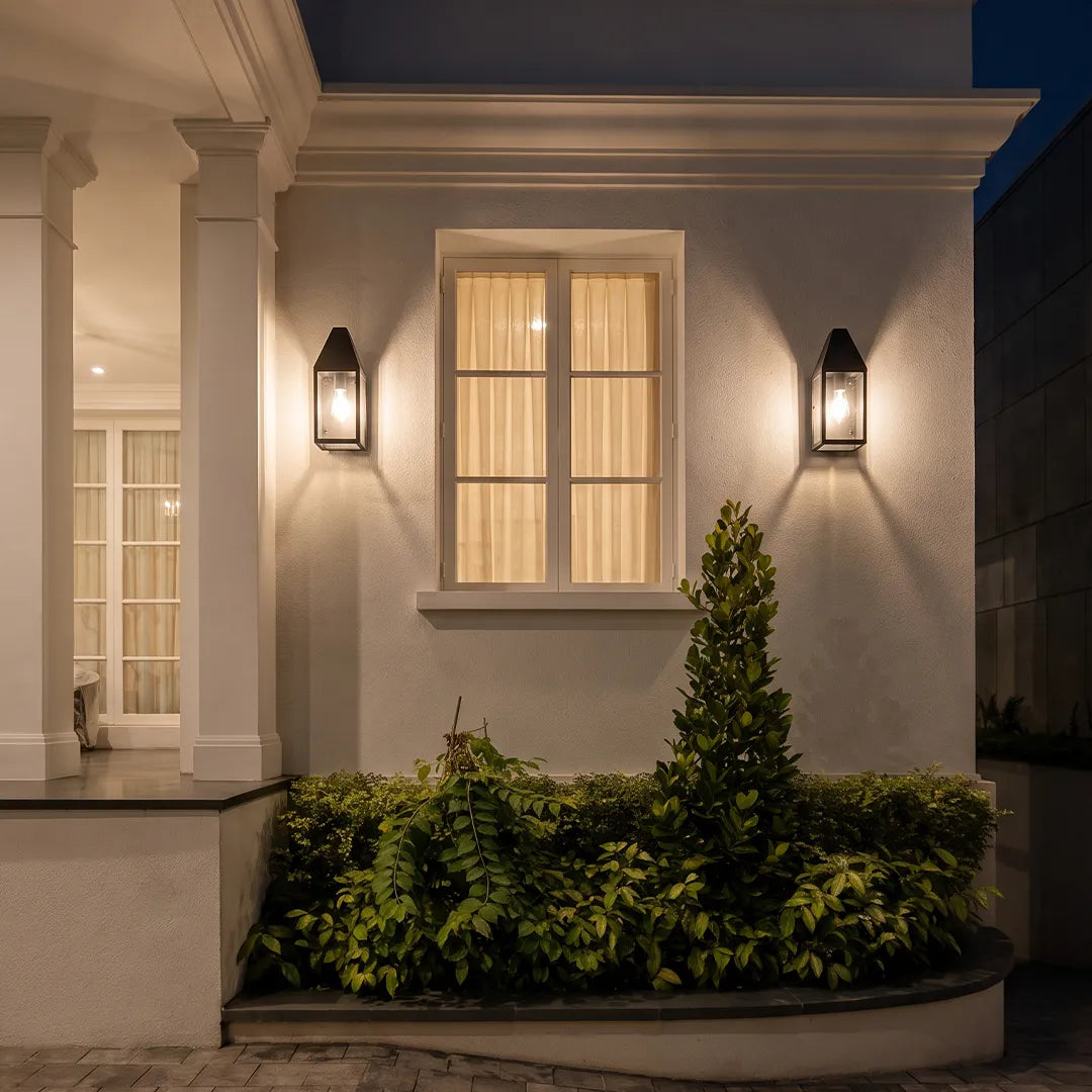 Outdoor black sconce placed on either side of a window, providing symmetrical exterior wall lighting at night.