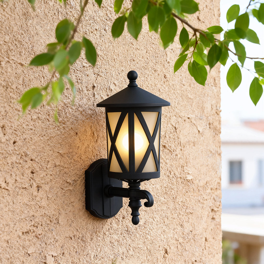Outdoor black wall light casting warm glow on beige exterior wall in bright daylight setting
