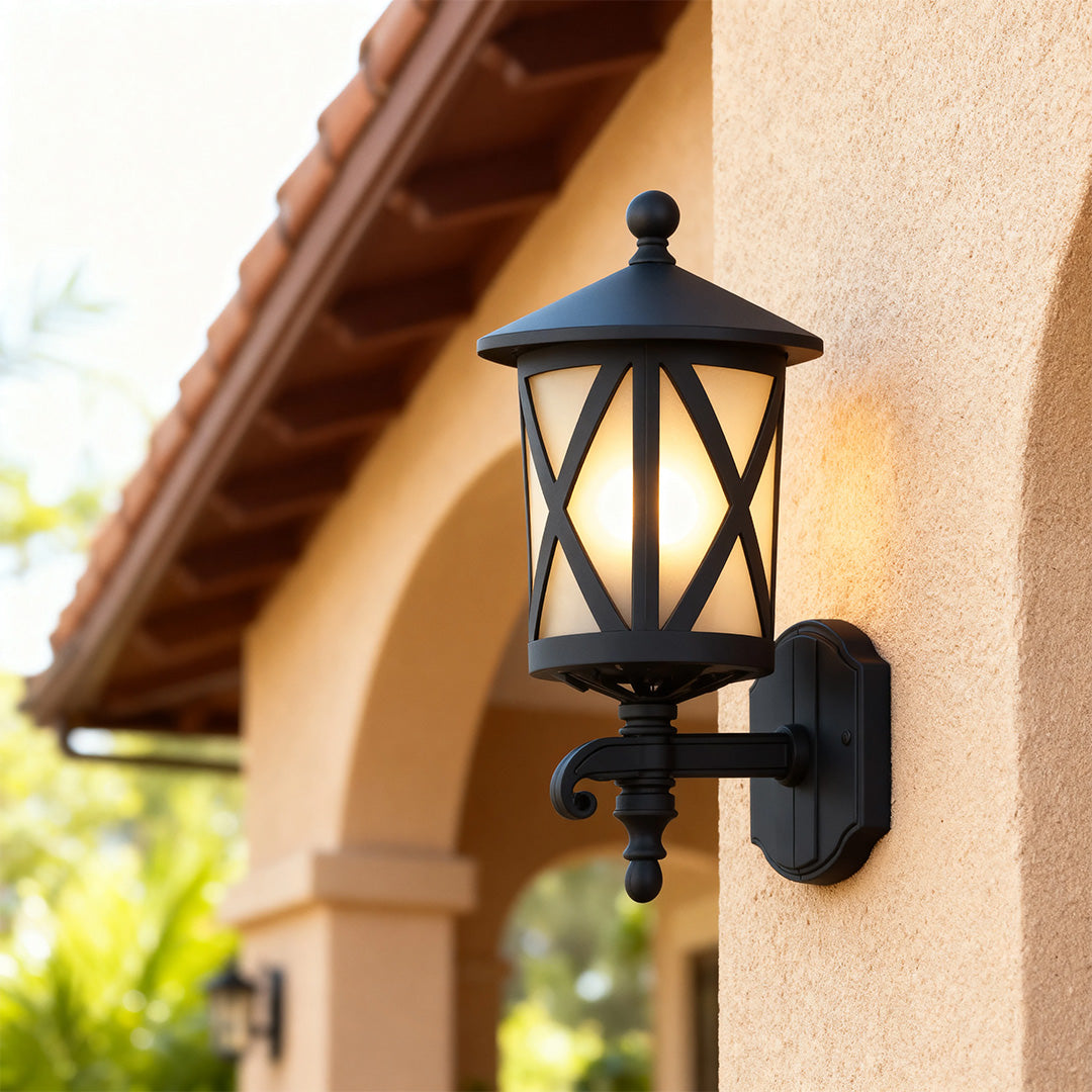 Close-up outdoor black wall light with crisscross design illuminating cream-colored stucco entrance wall