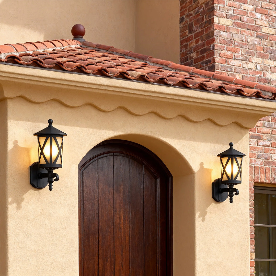 Pair of outdoor black wall lights flanking arched wooden door on Mediterranean style beige facade