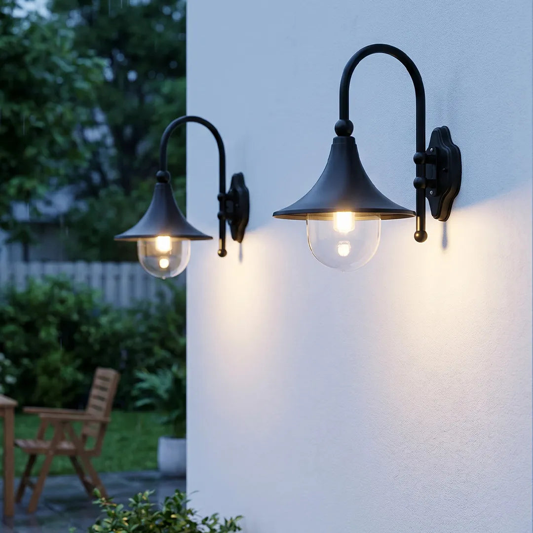 Pair of outdoor black wall lights installed on a white exterior wall, featuring gooseneck arms and clear glass shades.