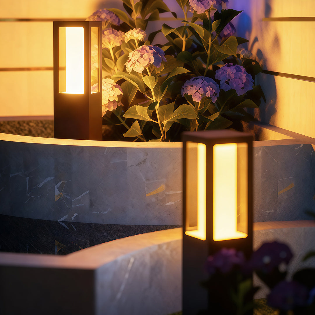 Outdoor bollard light installed along a garden pathway, providing warm and inviting illumination.