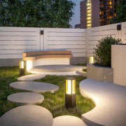 Outdoor bollard light in a garden with plants, adding a contemporary touch to the outdoor space.