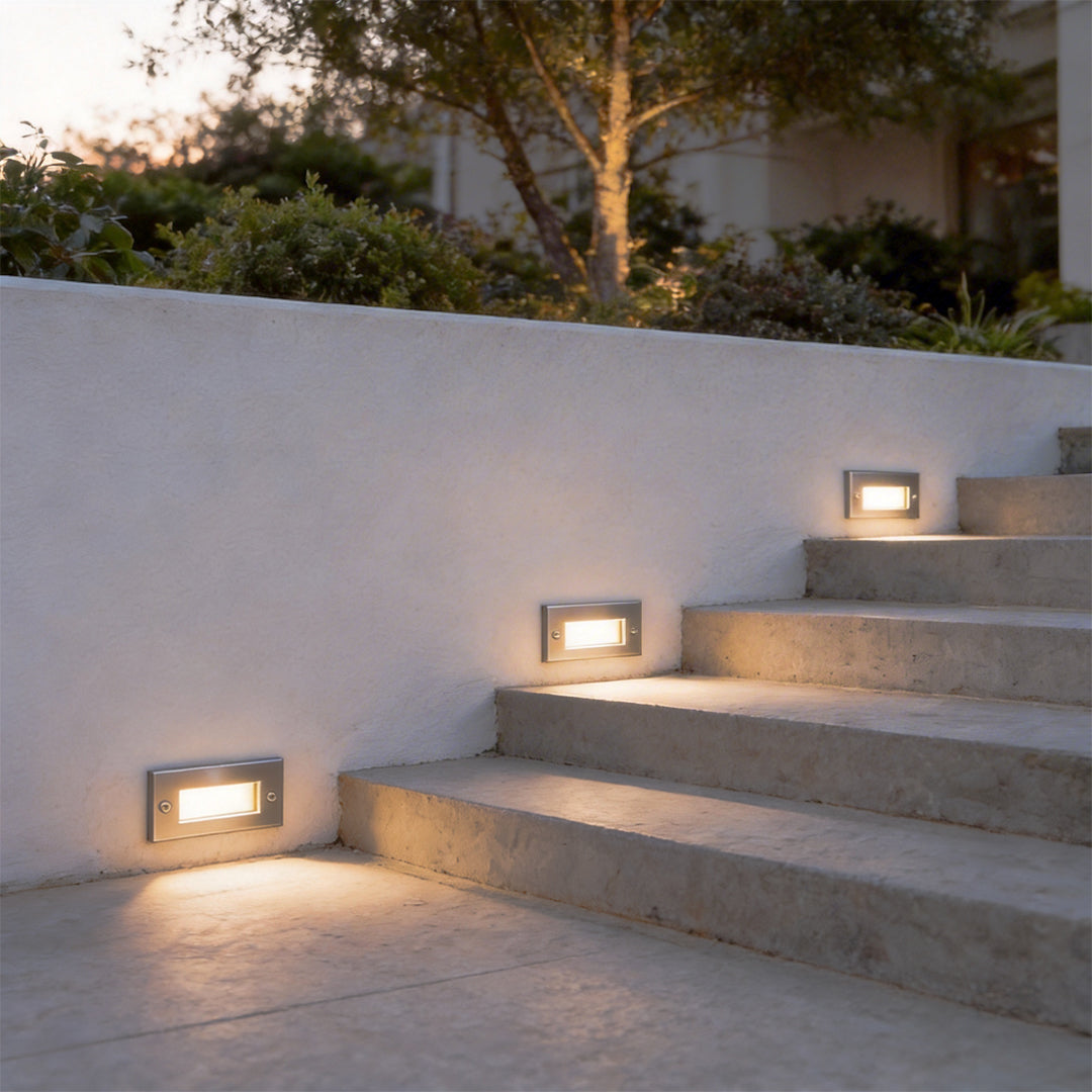 Outdoor brick light mounted on contemporary exterior steps, providing soft lighting along a minimalist stairway.