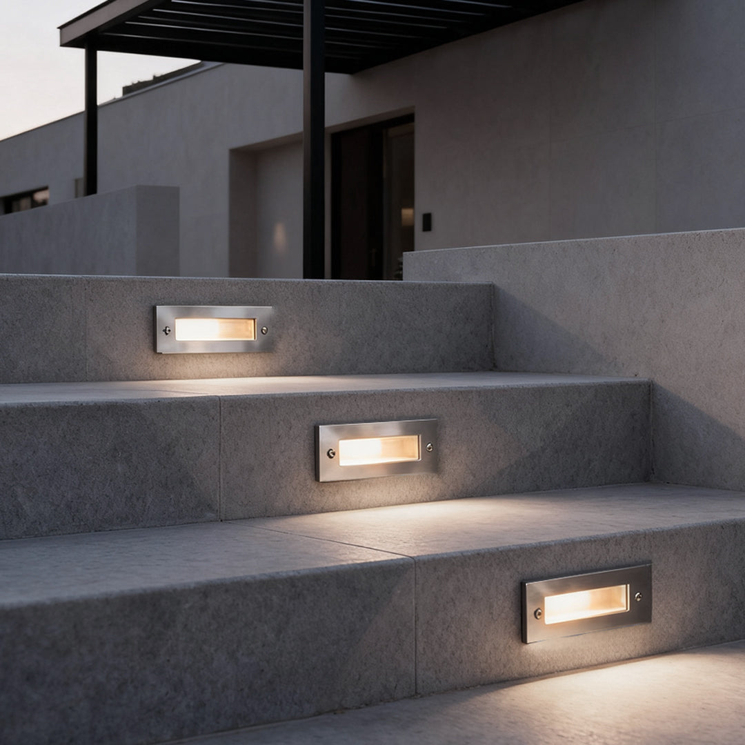 Outdoor brick light embedded in modern stone stair risers, providing subtle step illumination for a contemporary residential exterior.