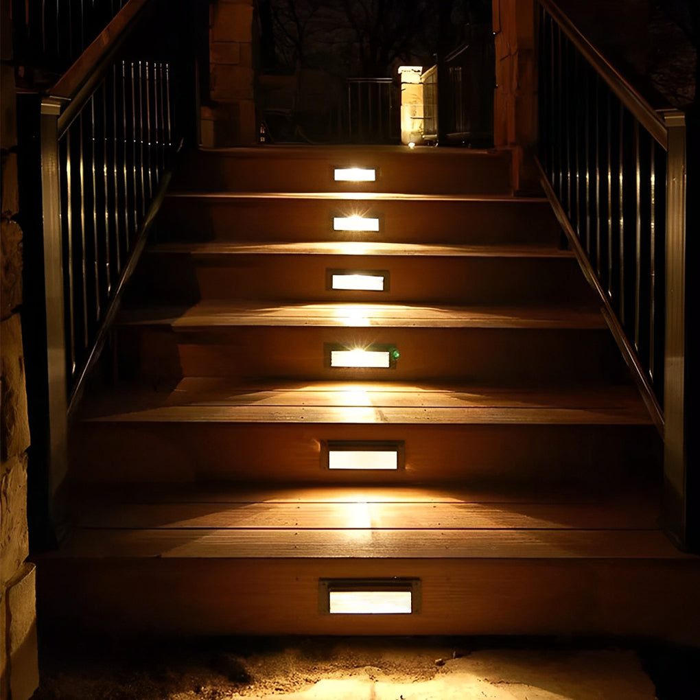 Outdoor brick light lining a staircase with metal railings, creating a welcoming glow and enhancing nighttime safety.