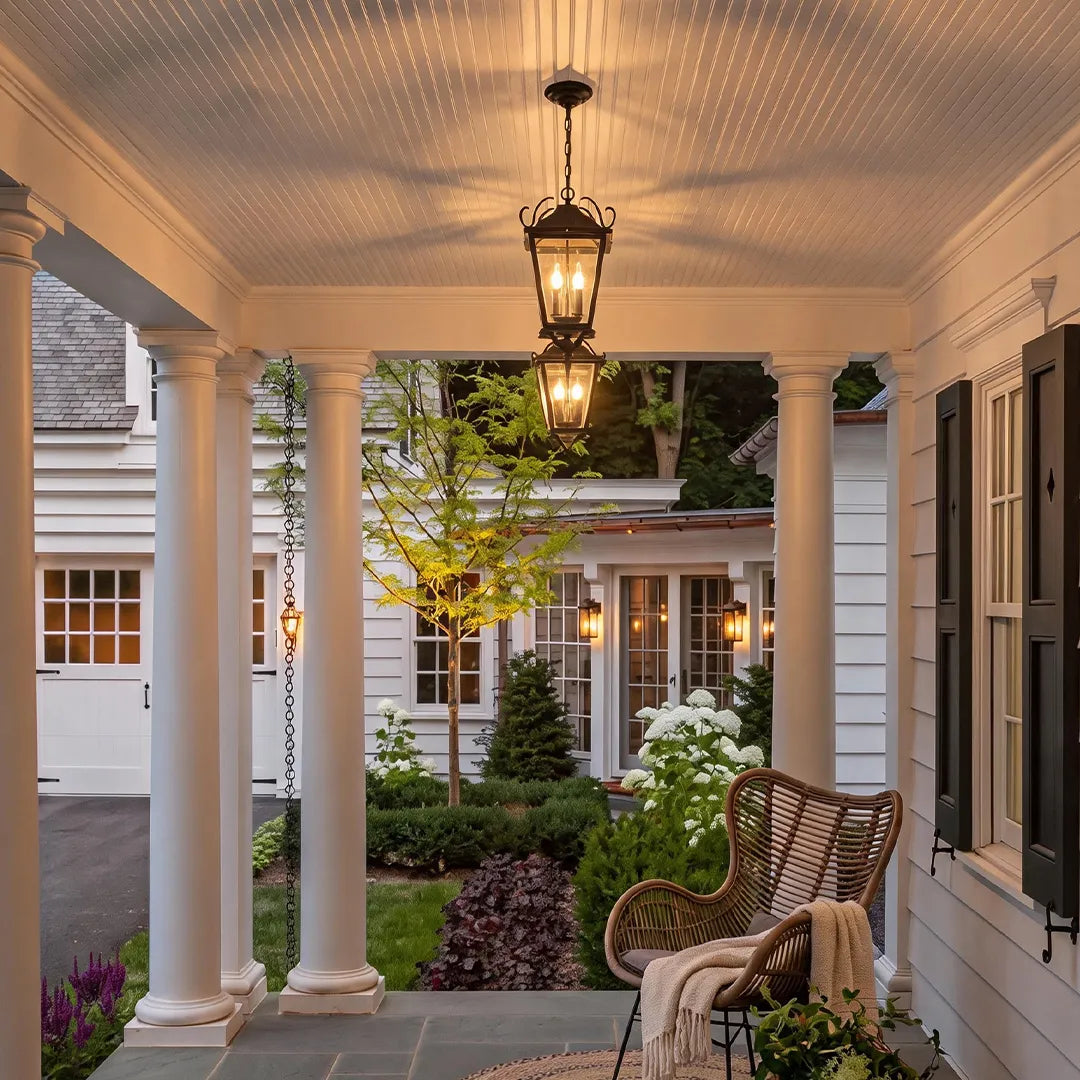 Outdoor ceiling pendant light centered on a covered porch with columns, bringing traditional style and warm ambient lighting.
