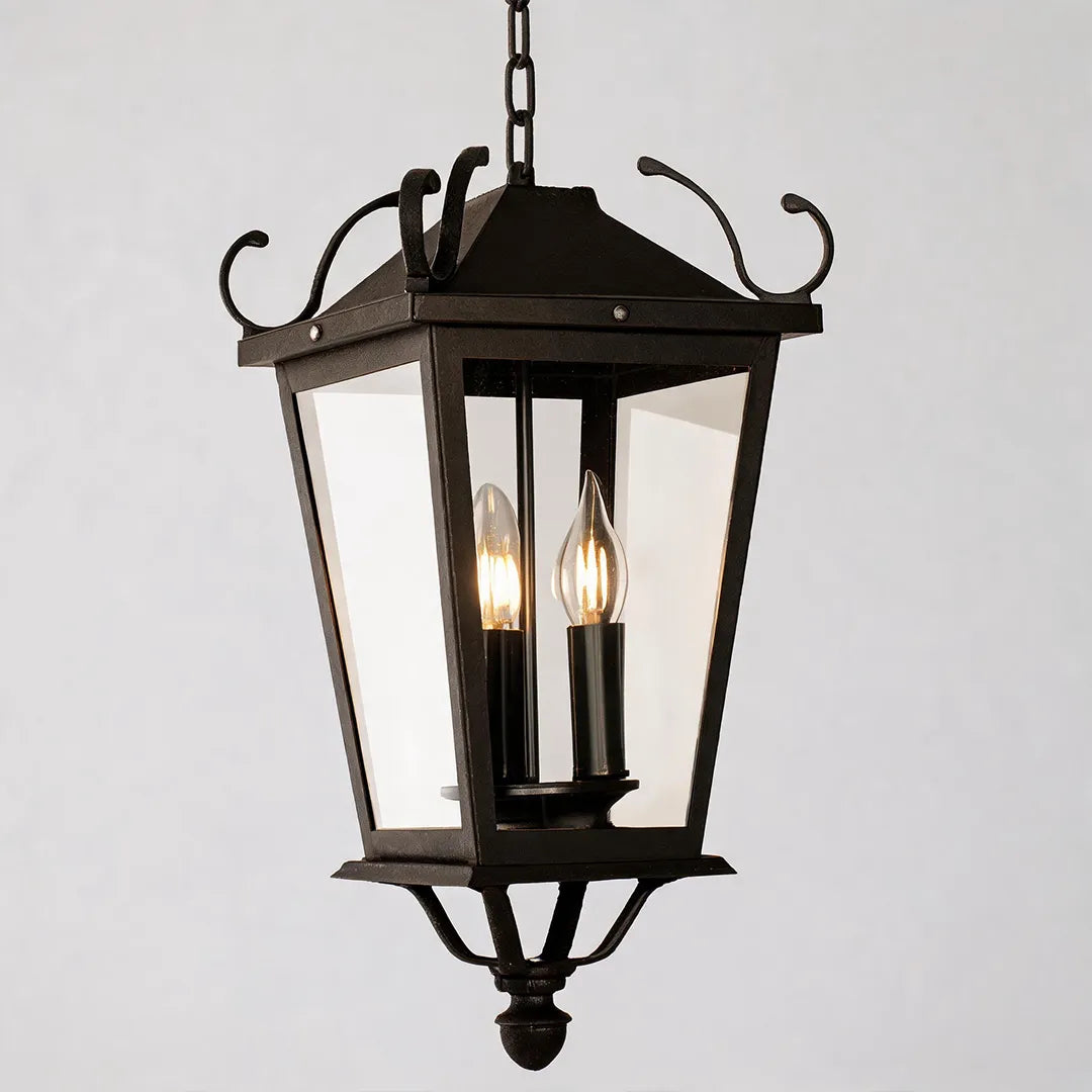 Outdoor ceiling pendant light close-up on a white background, featuring a black lantern frame with clear glass panels and candle-style bulbs.