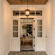 Outdoor ceiling pendant light hanging above a covered white brick entryway, adding classic lantern-style illumination to the front door.