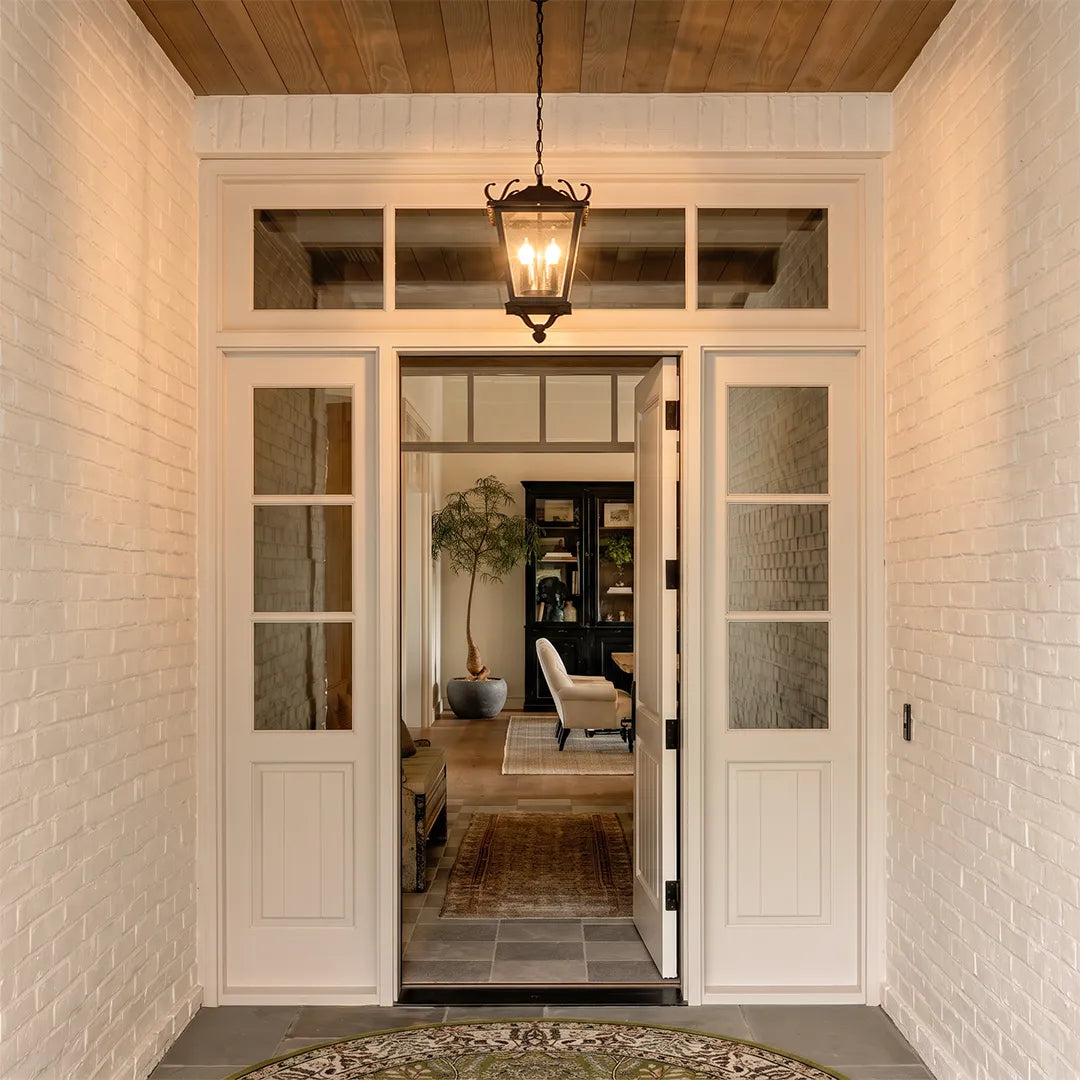 Outdoor ceiling pendant light hanging above a covered white brick entryway, adding classic lantern-style illumination to the front door.