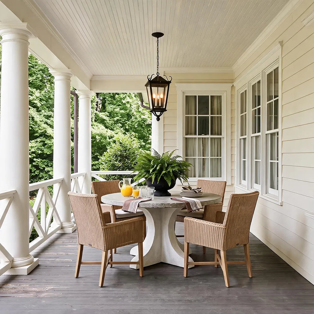 Outdoor ceiling pendant light illuminating a bright wraparound porch dining area, complementing the classic exterior design.