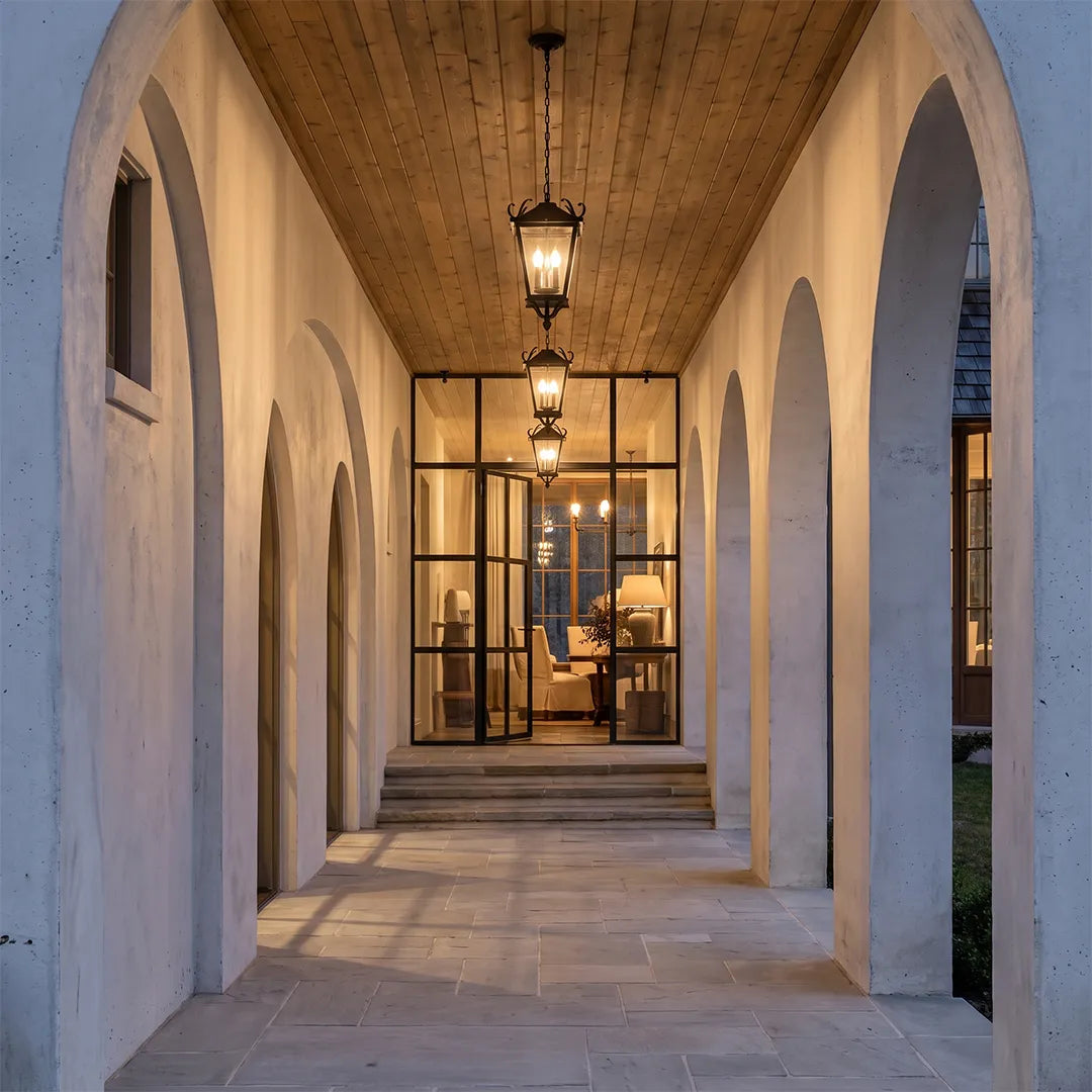 Outdoor ceiling pendant lights lining a long arched exterior corridor, creating a timeless and welcoming architectural look.