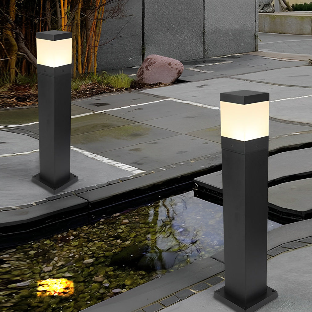 Outdoor commercial bollard lights with warm LED glow enhancing a landscaped garden and stone pathway.