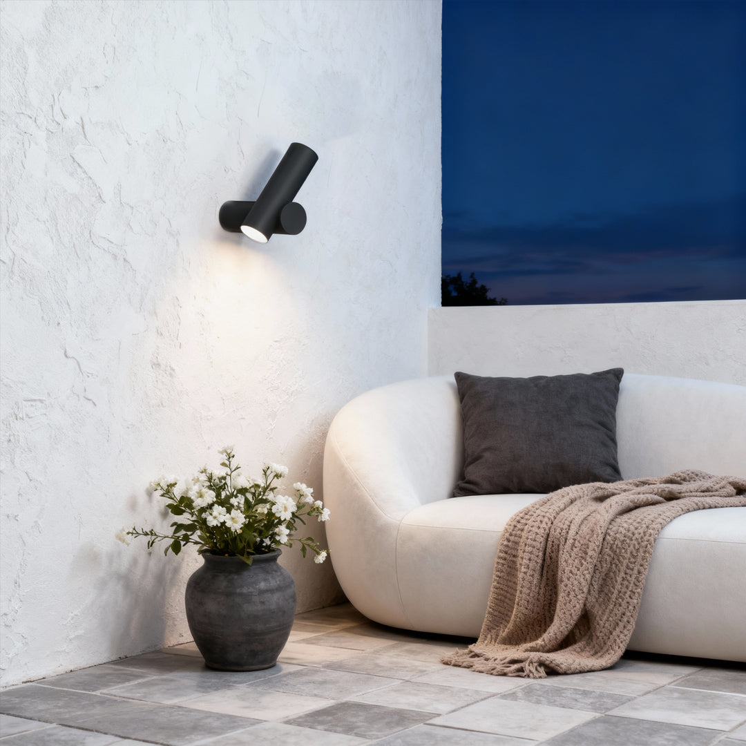Outdoor black spotlight wall lights mounted beside a cozy seating area, casting focused warm illumination.