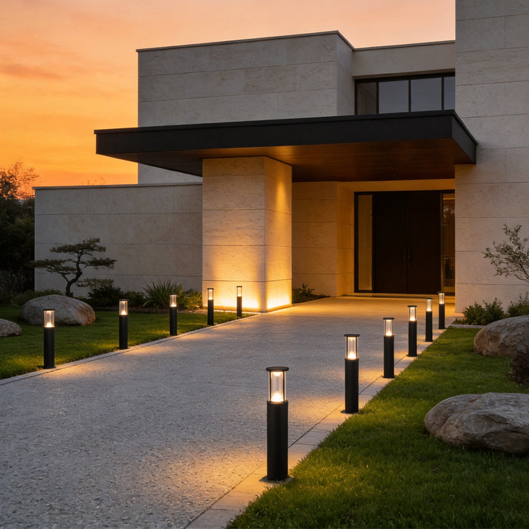 Elegant outdoor driveway with warm glowing Landscape Bollard Lights leading toward a modern luxury home at sunset.