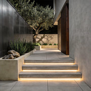 Outdoor embedded LED light strips illuminating modern staircase edges with warm, ambient glow.