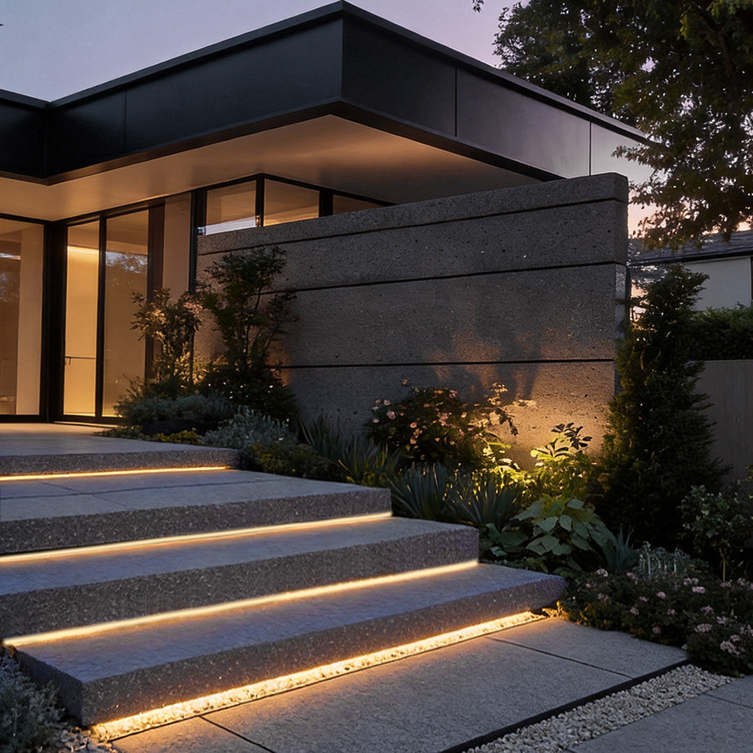 Outdoor embedded LED light strips providing soft illumination along a contemporary house entrance.
