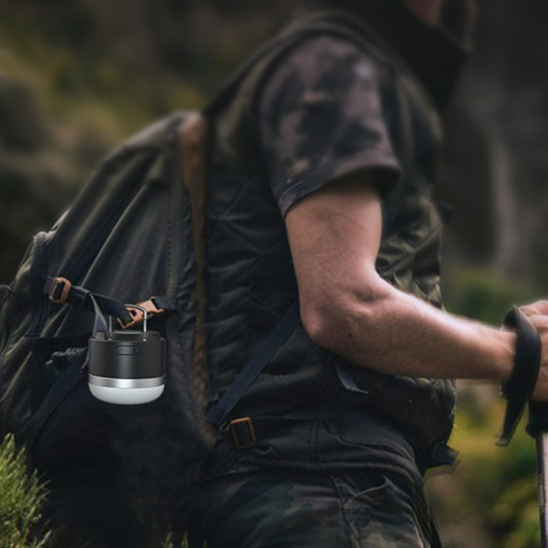 Outdoor enthusiast using bright LED lantern during nighttime camping expedition in forest setting