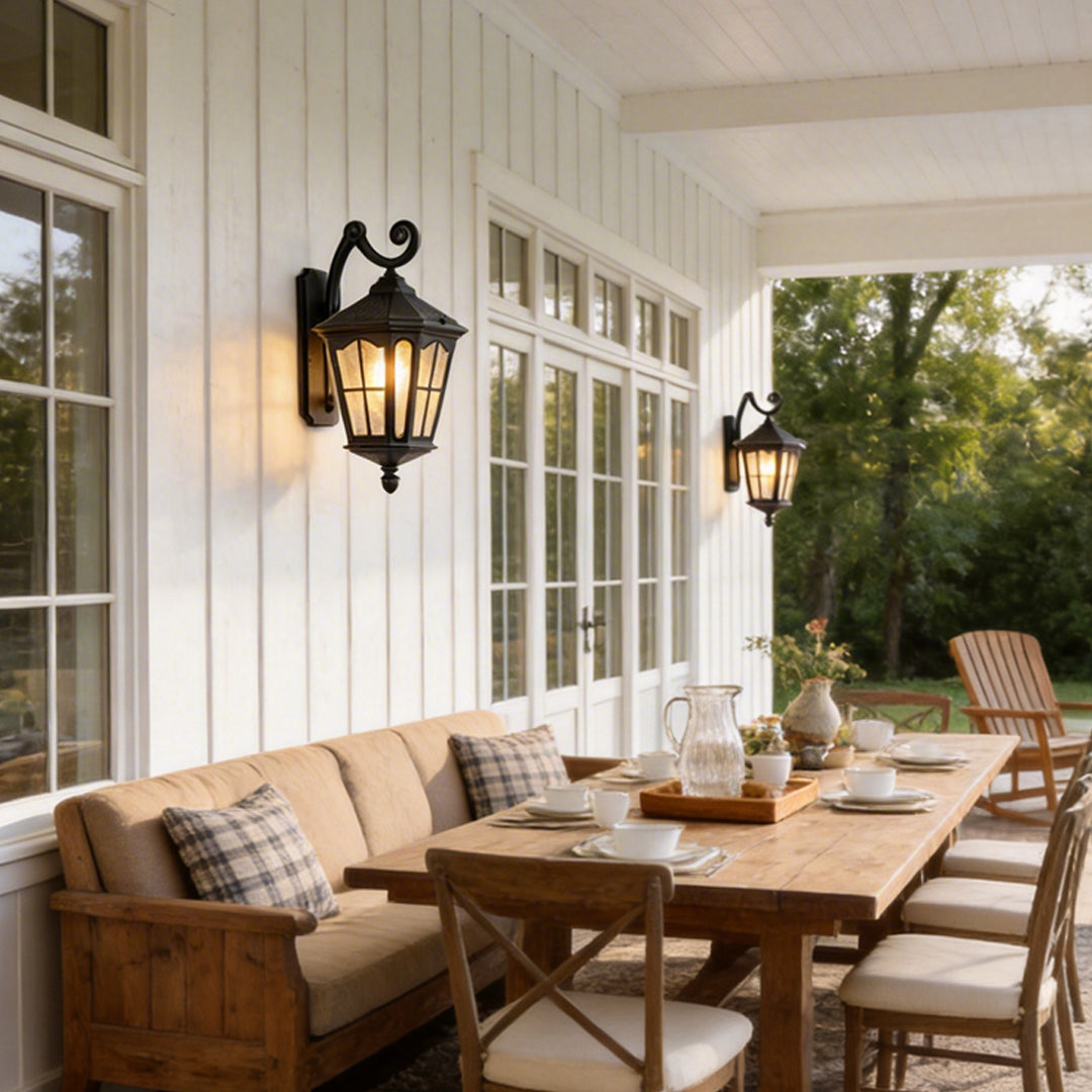Outdoor front porch lights with a black finish, providing warm light beside a seating area.
