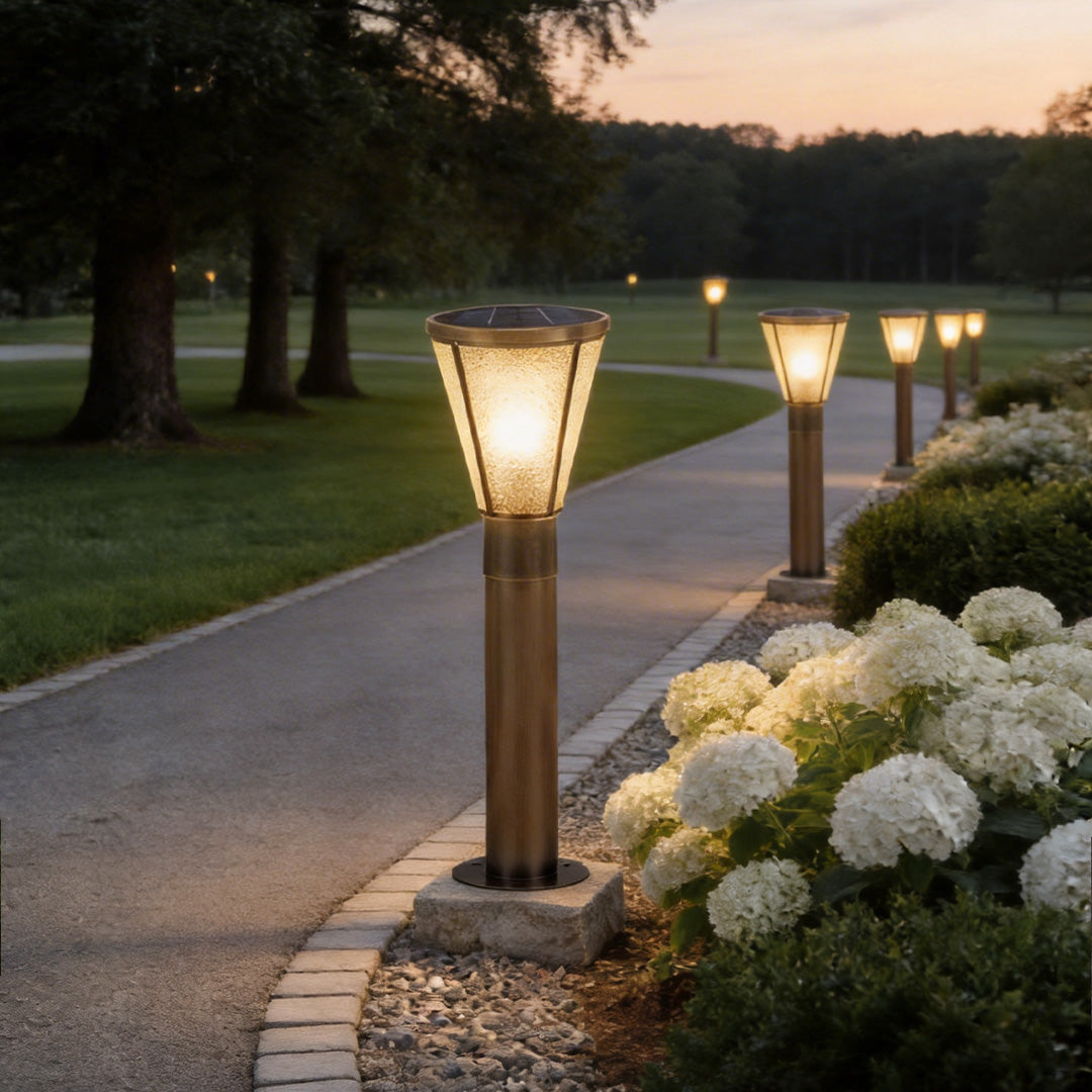 Outdoor garden path lights with a warm glow, illuminating a flower-lined pathway.