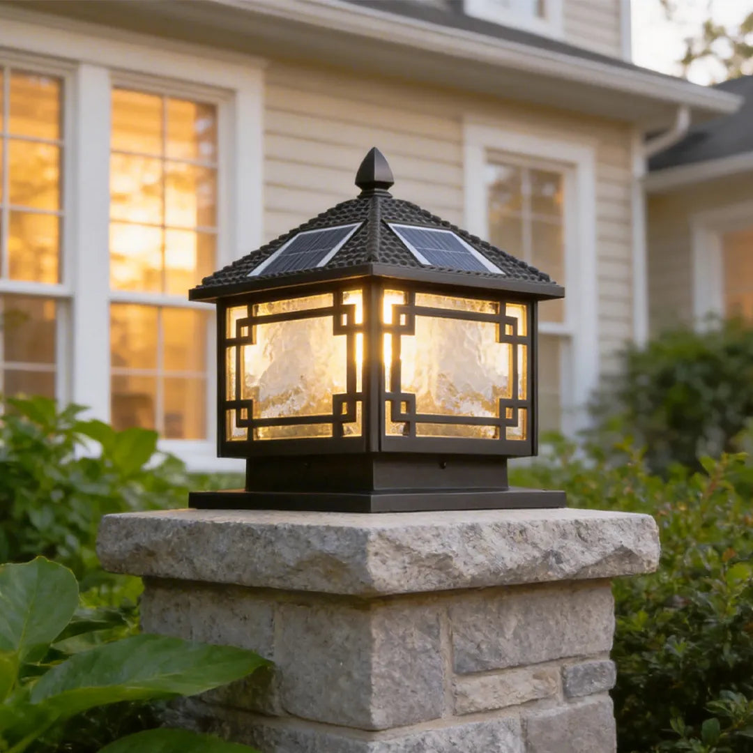 Outdoor garden pillar lights installed on a stone pillar beside a house exterior with warm evening illumination.