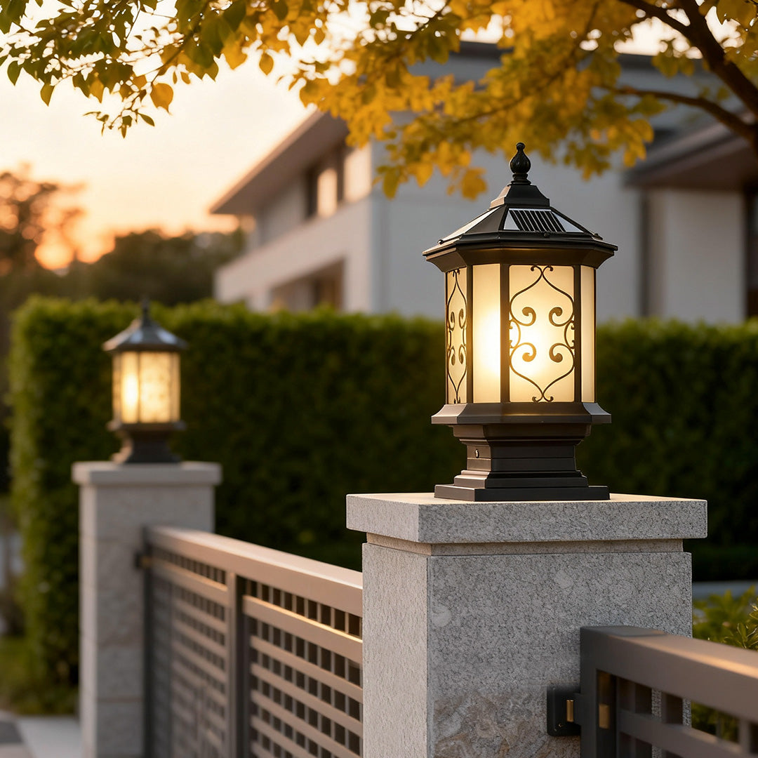 Outdoor gate pillar lights at sunset, casting a soft glow along a residential driveway.