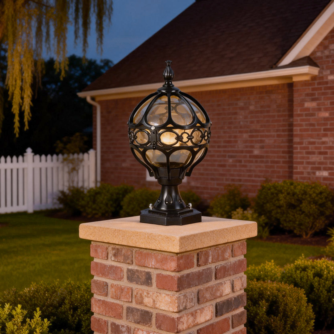 Classic outdoor globe pillar lights in black and gold, installed on a brick pillar in a residential garden.