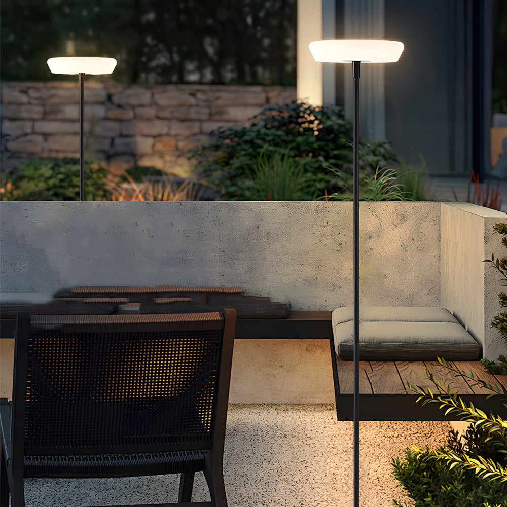 Outdoor patio setting with modern halo floor lamp providing warm illumination alongside wicker furniture and planters