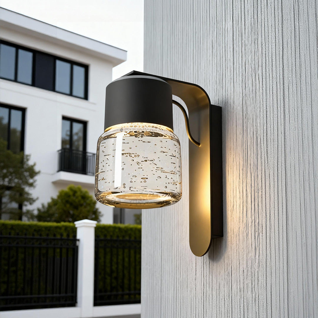 Exterior wall mount lights installed on outdoor wall with warm illumination and clear glass shade.