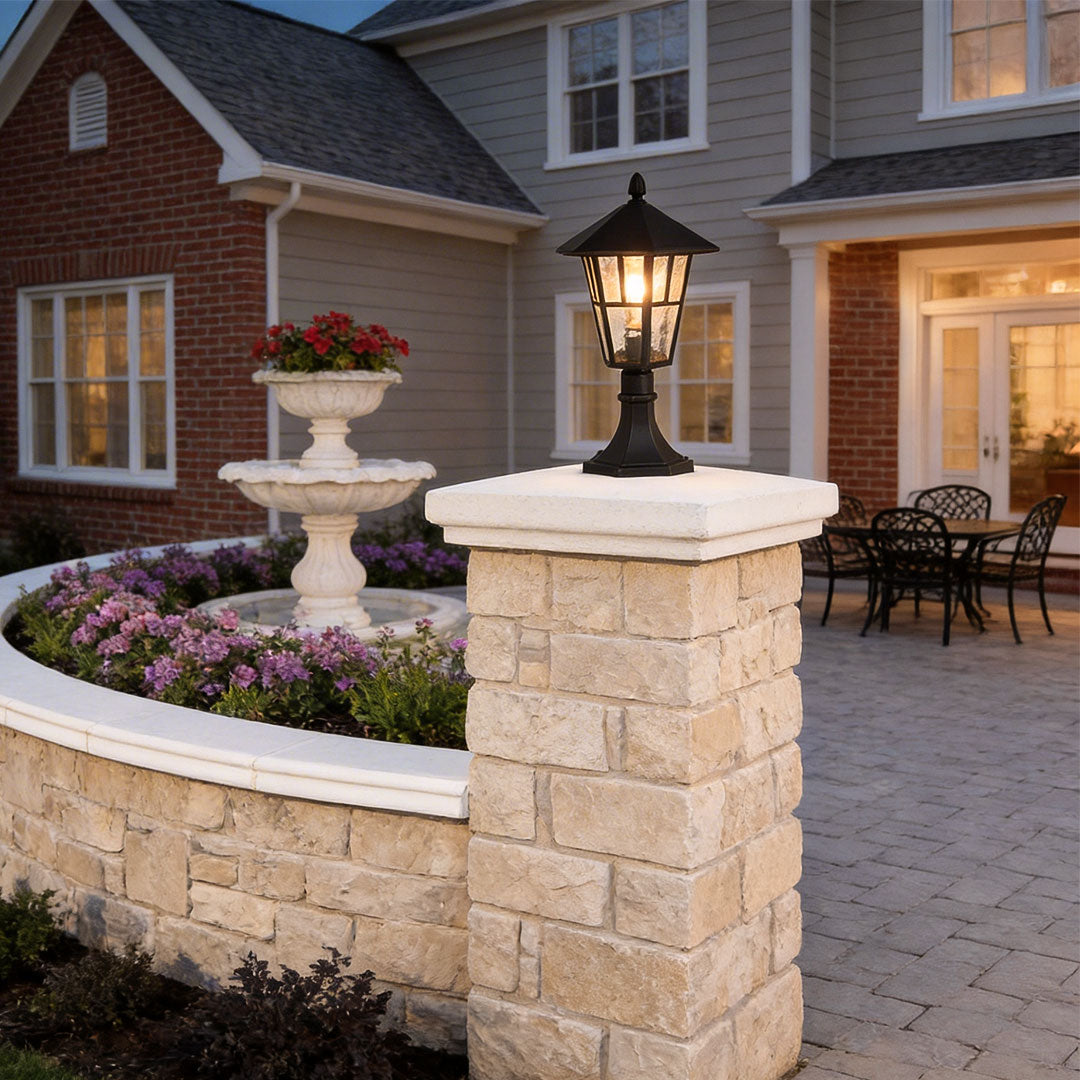 Outdoor landscape path lighting with a classic black design, mounted on a brick pillar near a garden.