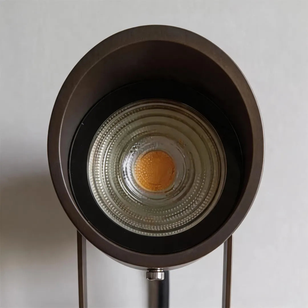 Outdoor landscape spotlight with round LED lens and bronze metal housing detail