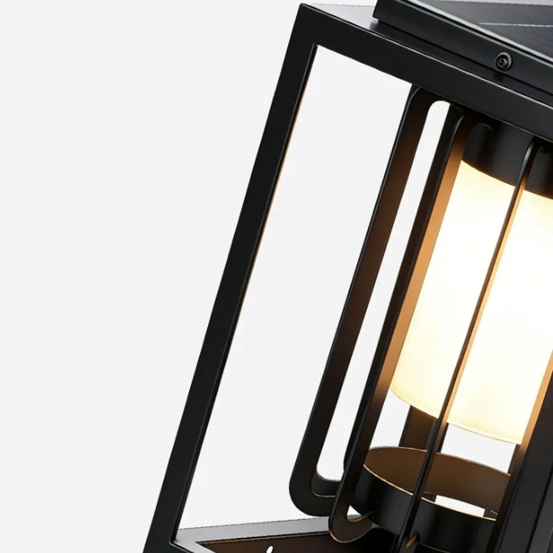 Angled close-up of an outdoor lantern light fixture showing the black metal frame and warm glowing shade.