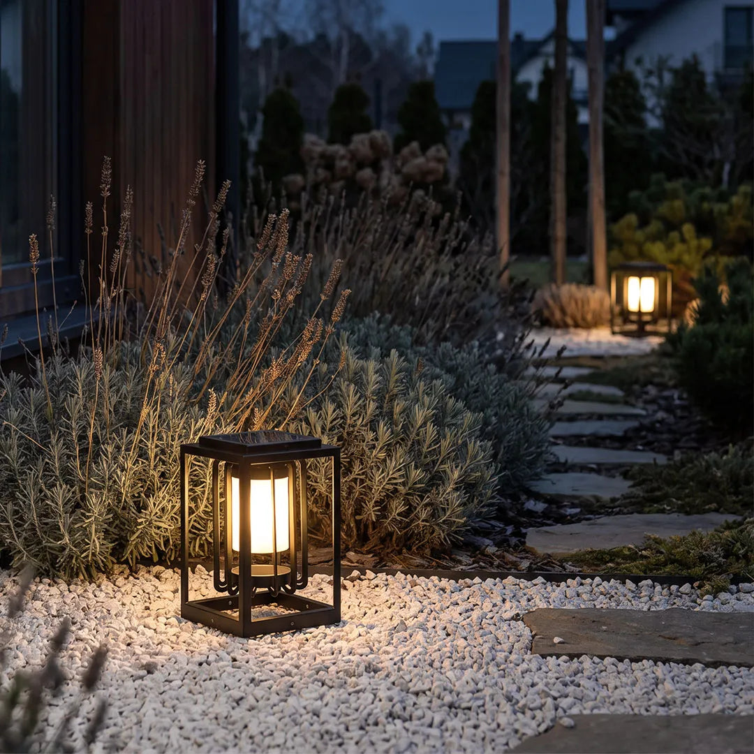 Outdoor lantern light fixture lighting a gravel garden path in a modern landscape at night.