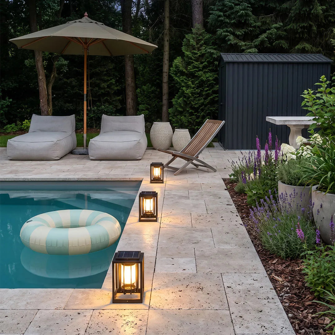 Outdoor lantern light fixture placed along a poolside patio with lounge chairs and soft evening lighting.