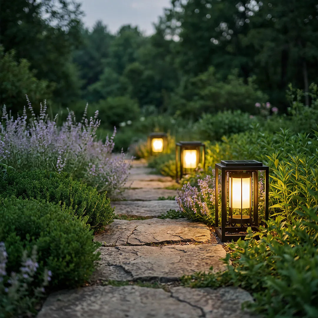 Outdoor lantern light fixture glowing beside a stone garden path bordered by lavender and greenery.