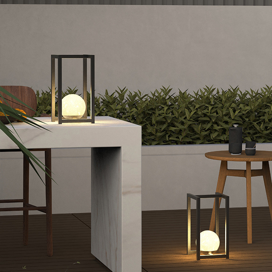 Outdoor lanterns black arranged near a seating area, producing cozy evening ambiance with warm light.