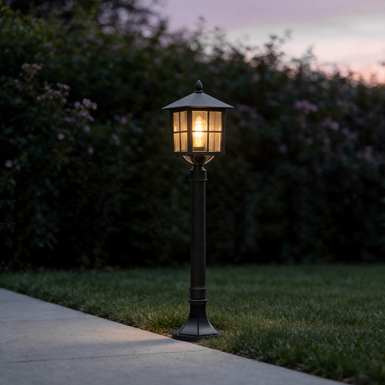 Outdoor lawn lights with a classic black design, illuminating a garden pathway at dusk.