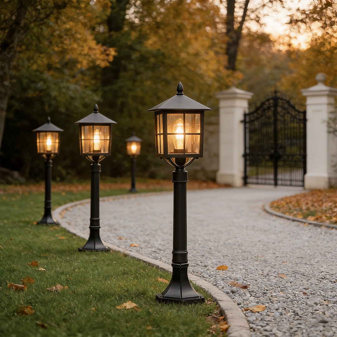 Outdoor lawn lights with a vintage style, providing warm illumination along a driveway.