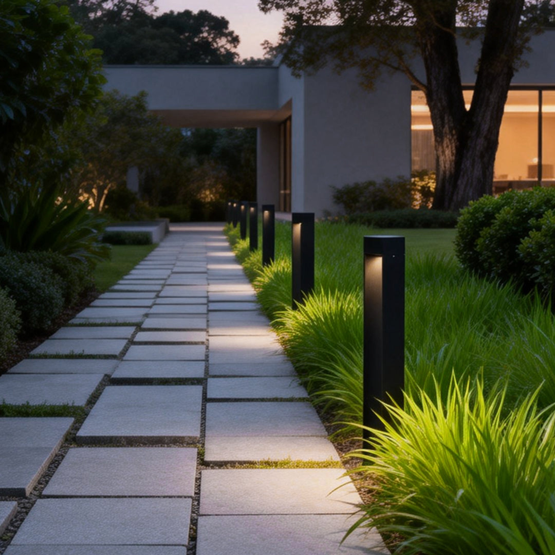 Outdoor LED bollard lights installed along a stone garden path at dusk.