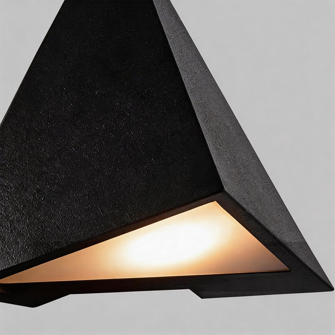 Close-up of outdoor LED wall sconce showcasing its triangular shape and warm light.