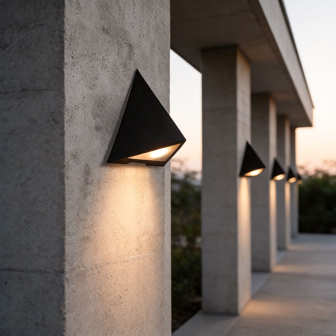 Outdoor LED wall sconce with a contemporary triangular design, enhancing a concrete pillar.