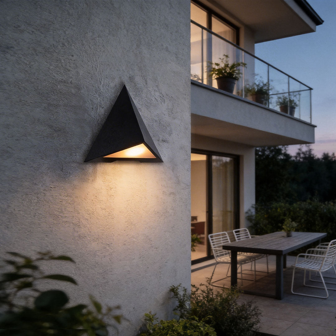 Outdoor LED wall sconce with a sleek triangular design, illuminating a modern balcony area.