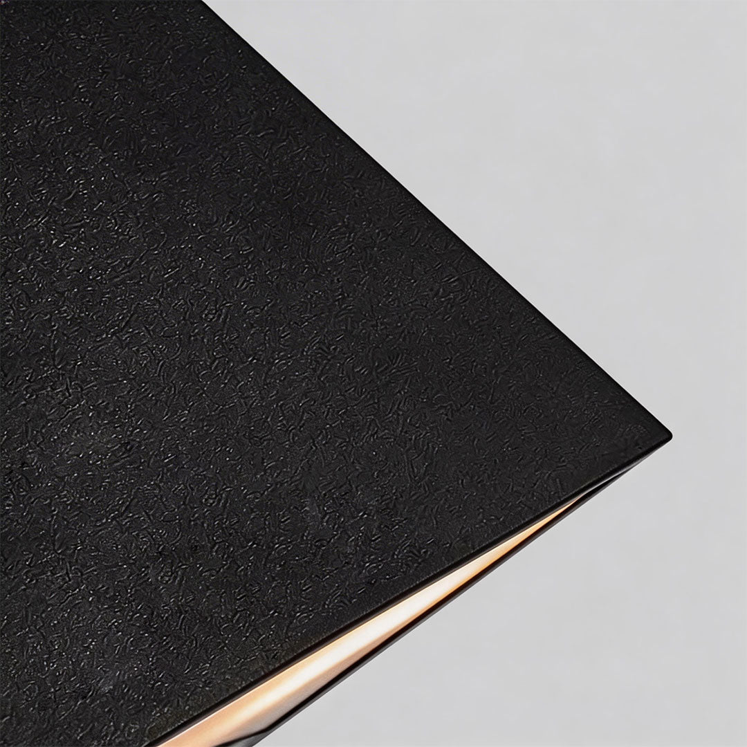 Outdoor LED wall sconce with a sleek triangular design, mounted on a stone wall.