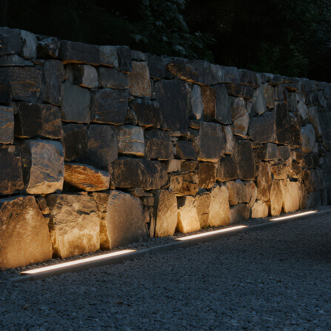 Outdoor LED wall wash lighting creating dramatic uplighting on textured stone facade with architectural accent