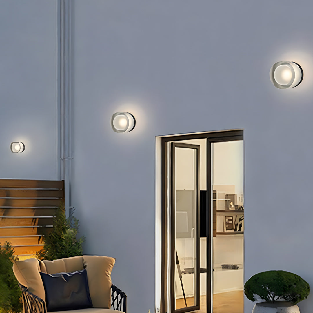 Modern outdoor light fixtures wall illuminating a house entrance with warm circular light patterns.