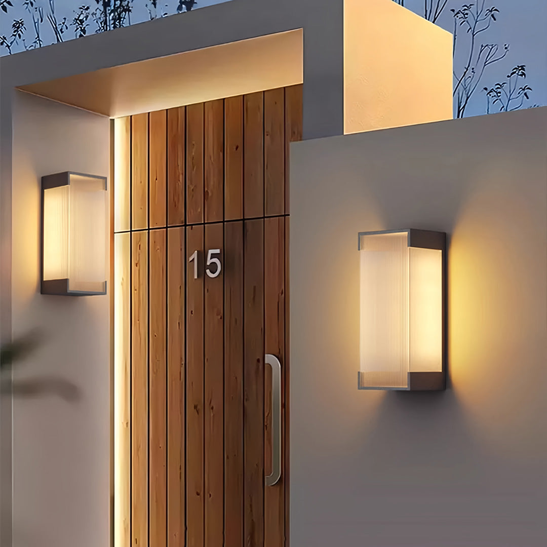Modern outdoor lighting fixtures wall mounted with gold body lighting a front entry pathway, creating a welcoming night ambiance.