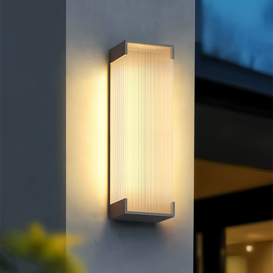 Warm glowing outdoor lighting fixtures wall mounted with frosted glass and gold trim enhancing a modern home exterior.