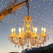 Outdoor lighting hanging with crystal details, illuminating a garden archway at dusk.